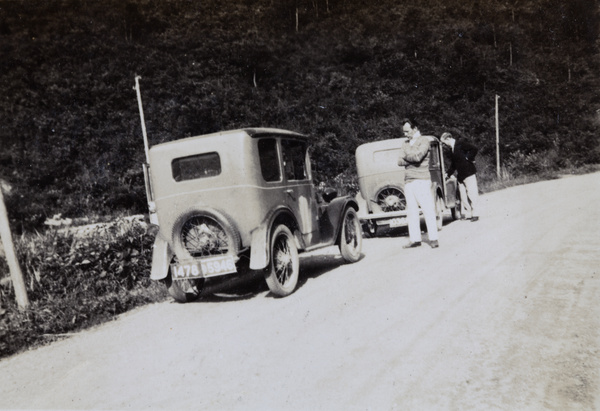 Two men and two cars at the side of a road