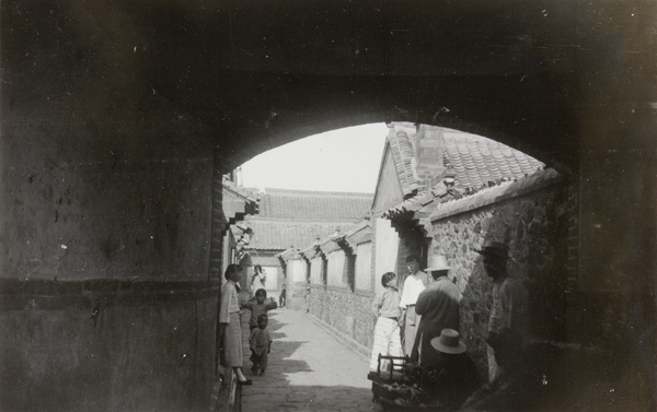 People in a back alley, with an itinerant fruit seller