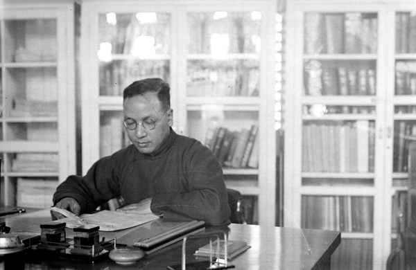 Fu Bingchang reading a newspaper in an office