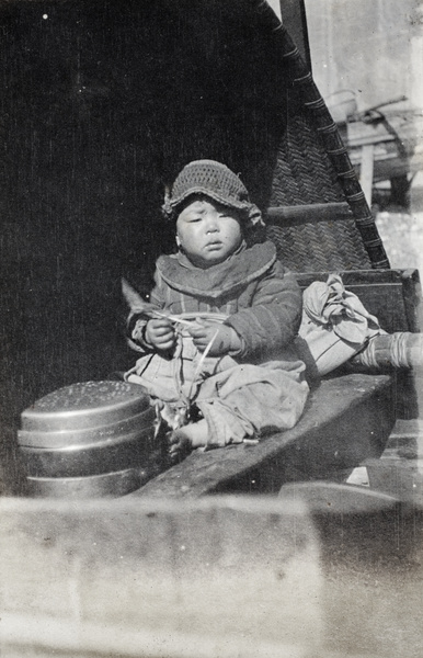Boat-dwelling child wearing a crochet hat on a river boat, Shanghai