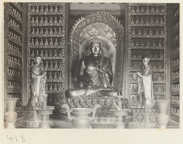 Temple interior showing statues of Buddha and attendants, ritual objects, and walls with Bodhisattva reliefs at Wan shou si