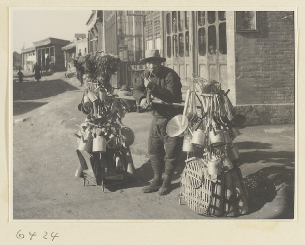 Household goods vendor with his wares loaded onto a shoulder carrying pole