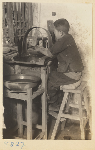 Boy using a grinding wheel to polish jade in a workshop