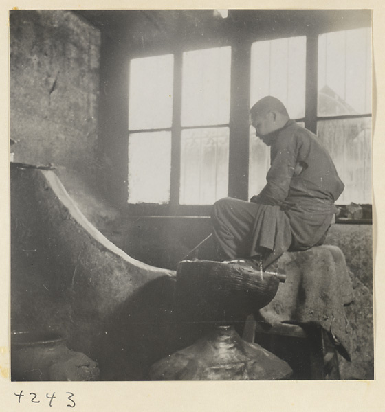 Man stirring sesame oil in a metal vat in a sesame oil shop