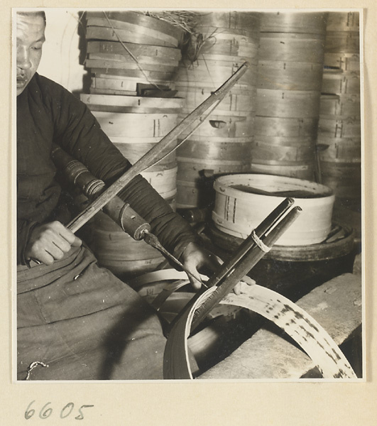 Man drilling holes in the rim of a bamboo steamer in a workshop