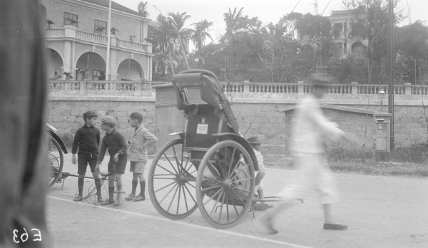 Boys with a wire bicycle, and rickshaws, Holts Wharf, Hong Kong