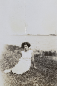 A young woman sitting near a river bank