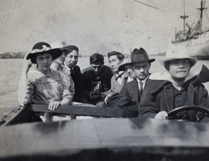 Hannah at the wheel of a motorboat with Tom Hutchinson and other passengers, Huangpu, Shanghai
