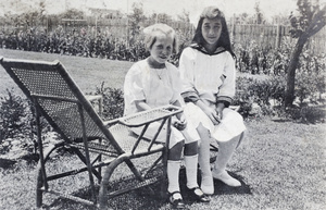 Maggie Hutchinson sitting on a wicker lounger with neighbouring girl, 35 Tongshan Road, Hongkou, Shanghai