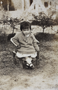 Bea Hutchinson wearing a hand knitted jumper, sitting in a small bamboo chair in the garden, 35 Tongshan Road, Hongkou, Shanghai