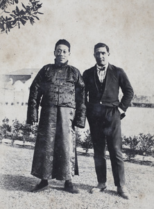 Charles Hutchinson, wearing a fashionable western suit, with an unidentified man, wearing a silk Chinese jacket, in the garden, 35 Tongshan Road, Hongkou, Shanghai