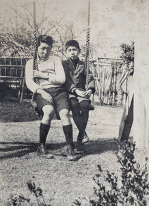 Dick and Fred Hutchinson sitting together on a garden swing, 35 Tongshan Road, Hongkou, Shanghai
