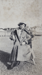 Molly Noble, wearing a winter coat and hat, sitting in the garden, 35 Tongshan Road, Hongkou, Shanghai
