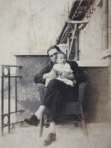 Mr E. D. Bush sitting with a baby holding a rattle, Shanghai