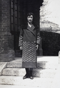 Maggie Hutchinson wearing a coat embellished with needlework, standing on the steps to 35 Tongshan Road, Hongkou, Shanghai