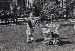 Gladys Hutchinson walking with a toy pram holding a teddy bear and doll, in the garden of 35 Tongshan Road, Hongkou, Shanghai