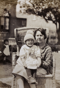 Thelma Thiis, wearing a hand knitted pom-pom hat, sitting with her aunt, Nellie Thomas, in the garden, 35 Tongshan Road, Hongkou, Shanghai 