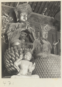 Temple interior showing statues of Bodhisattvas sitting on lotus thrones and attendant at Fa yuan si