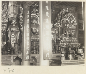 Temple interior showing altar with four Buddha statues, ritual objects, and columns with inscriptions at Fa yuan si