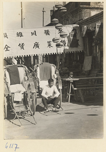 Street scene with rickshaws, rickshaw puller, and shop signs for a cotton shop (center) and a noodle shop (right)