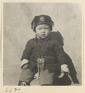 Child wearing a hat and a pendant