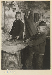 Boys heating metalworking tools in a workshop that makes iron pictures