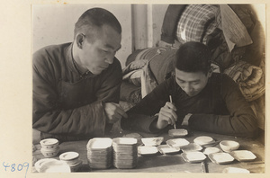 Two men making enamel dishes in a workshop