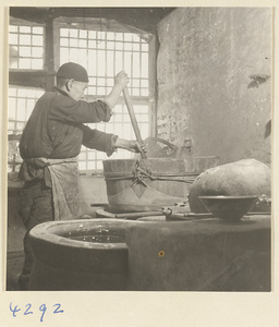 Man stirring the contents of a vat in a tofu-making shop