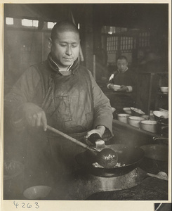 Restaurant interior showing a chef frying food in a wok