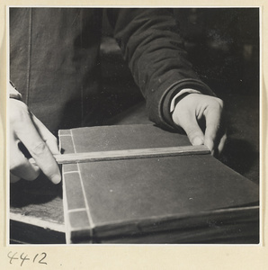 Man measuring the side-sewn binding of a book