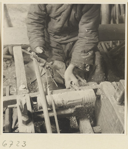 Carpenter turning a piece of wood at a lathe