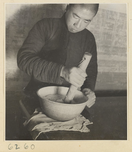 Interior of a scroll-mounting shop showing a man mixing paste called hu or jiang hu with water