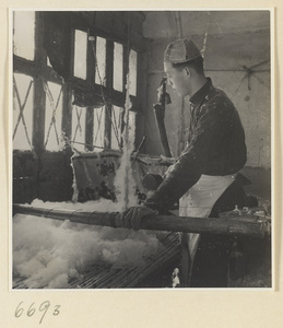 Man preparing cotton for spinning in a workshop