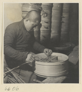 Man adding slats to a bamboo steamer in a workshop