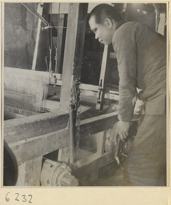 Interior of copper-net factory showing a man adjusting a loom