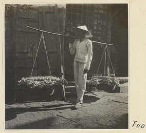 Man carrying a shoulder pole with baskets of produce on a street in Tai'an