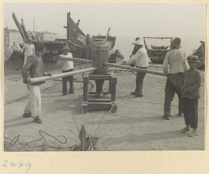 Four men turning a large winch on the beach in a fishing fillage on the Shandong coast
