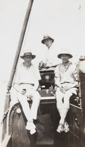 Three men on a boat with a wind-up gramophone player