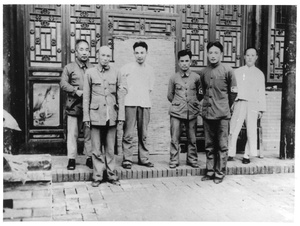 A group of six men gathered outside a building