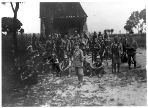 A group of soldiers in front of a barn