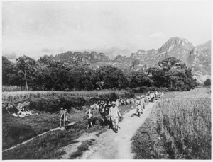 Soldiers walking on a track between fields