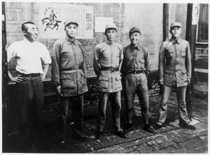 Staff of sub-district Headquarters (Xiao Fang on the left) in front of a wall with posters, Central Hebei province