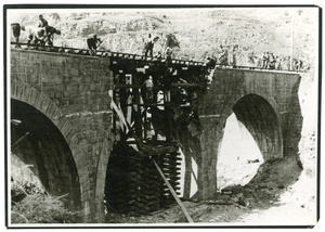 Workers repairing a bridge over a dried up river bed
