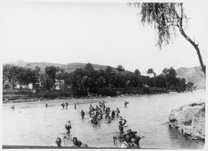 Villagers (refugees) fording a river with their possessions