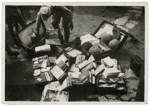 A Chinese army officer inspecting opened suitcases, containing books, photographs, and helmets
