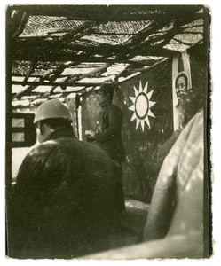 A man addressing a meeting in front of a picture of Chairman Mao
