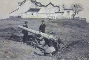 Two men in suits beside a cannon, with gunners, on Tortoise Hill, Hanyang